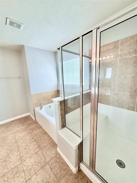 Luxurious primary bath featuring a sleek glass-enclosed shower and a relaxing soaking tub, perfect for unwinding.