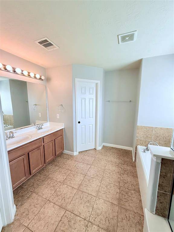 Spacious primary bath featuring dual sinks, modern fixtures, and a relaxing soaking tub for ultimate comfort.