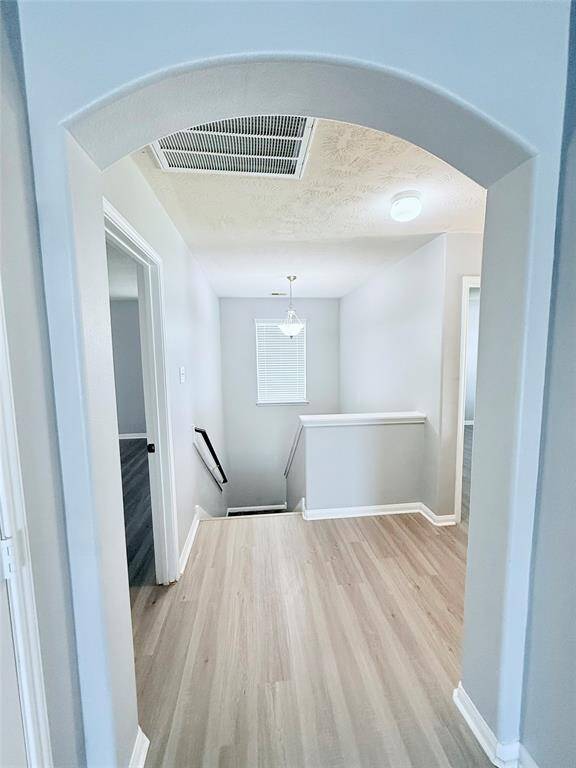 Bright and inviting hallway with modern flooring, leading to the downstairs area.