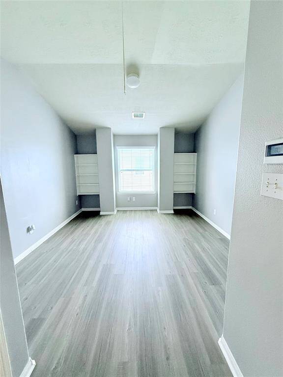 Spacious and bright game room featuring modern flooring and built-in shelves, perfect for entertainment and relaxation.