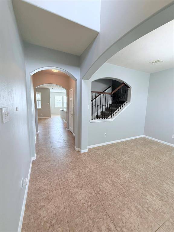 Welcome home to an inviting entryway featuring elegant arches and a spacious hallway leading to an open living area.