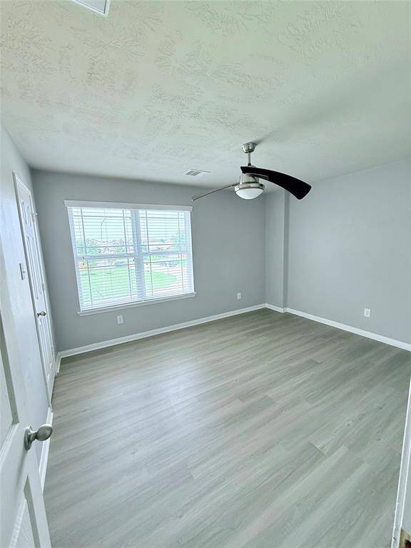 Bright and airy second bedroom featuring sleek flooring, ceiling fan and a large window for natural light.