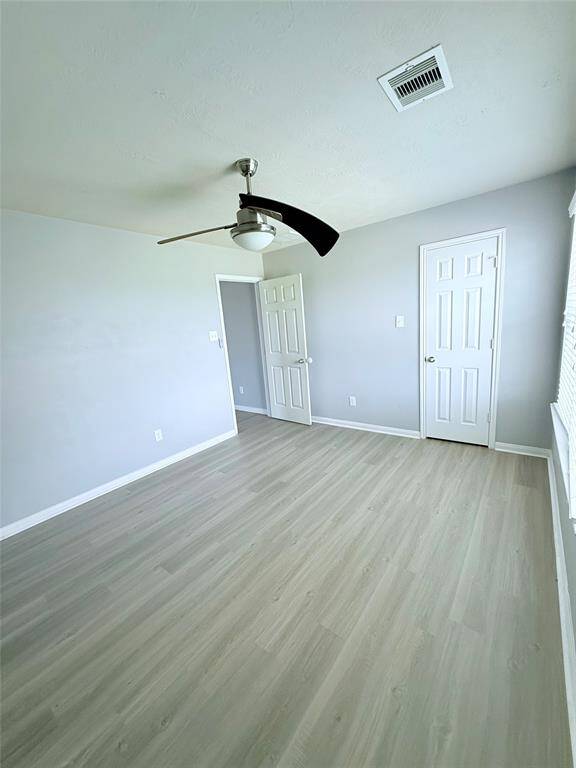 Bright and inviting second bedroom with fresh flooring, a modern ceiling fan, and ample natural light.