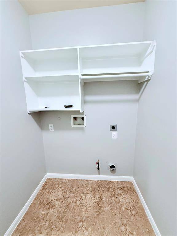 Efficient laundry room featuring ample shelving and convenient hookups, perfect for streamlined organization and ease of use.