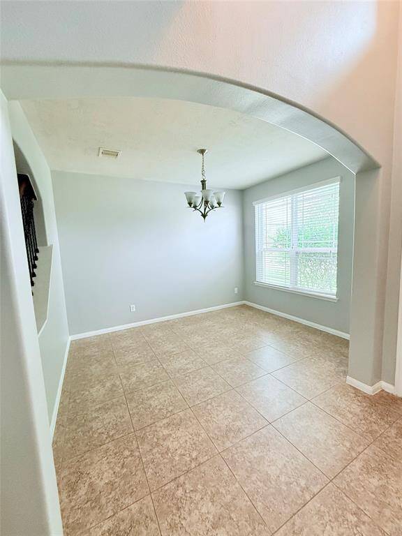 Bright and inviting dining room featuring elegant tile flooring, a stylish chandelier, and a large window for plenty of natural light. Perfect for gatherings and memorable meals.
