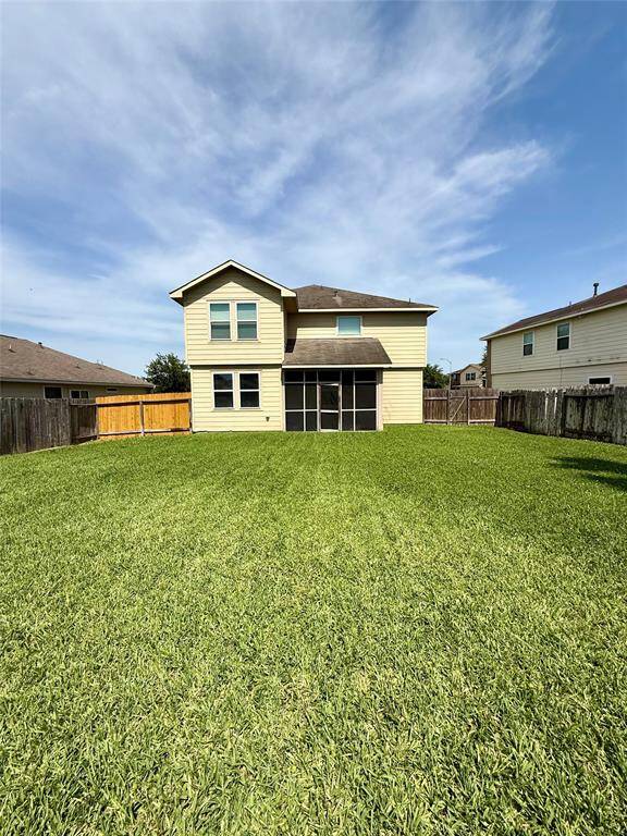 A spacious two-story home with a large, well-maintained backyard. It features a screened-in porch and is surrounded by a wooden fence for privacy. Ideal for outdoor activities and entertaining.