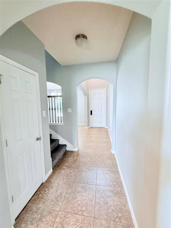 This hallway features a tiled floor, soft gray walls, and an arched doorway.