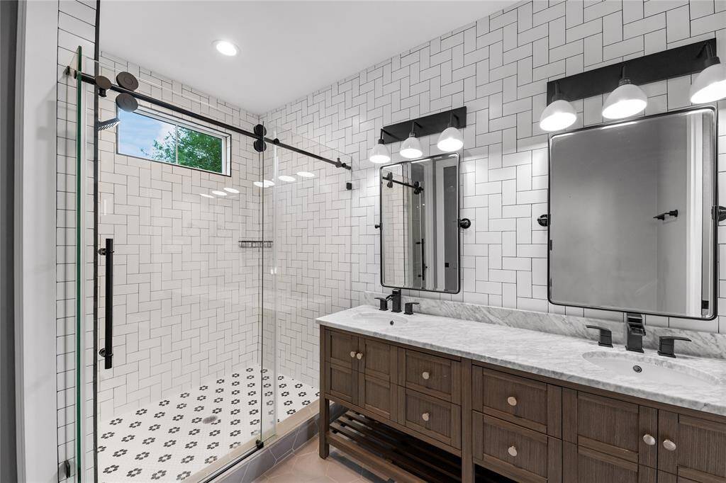 The en-suite bath features a grand frameless shower and dual-sink vanity, offering the perfect blend of elegance and functionality.