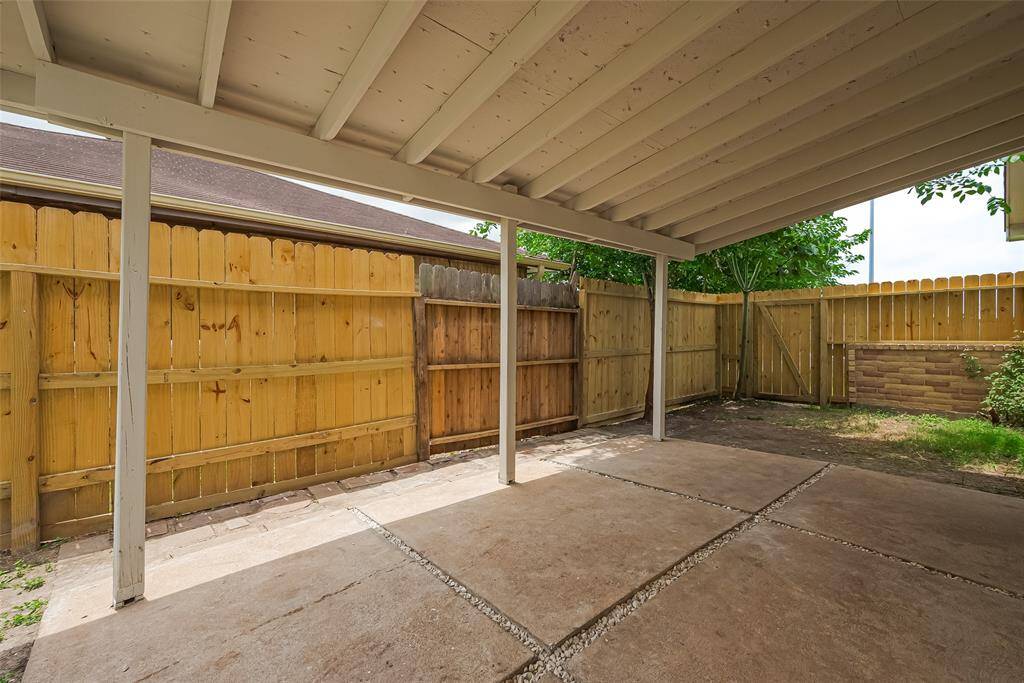 Covered patio space with a fresh fence and concrete areas