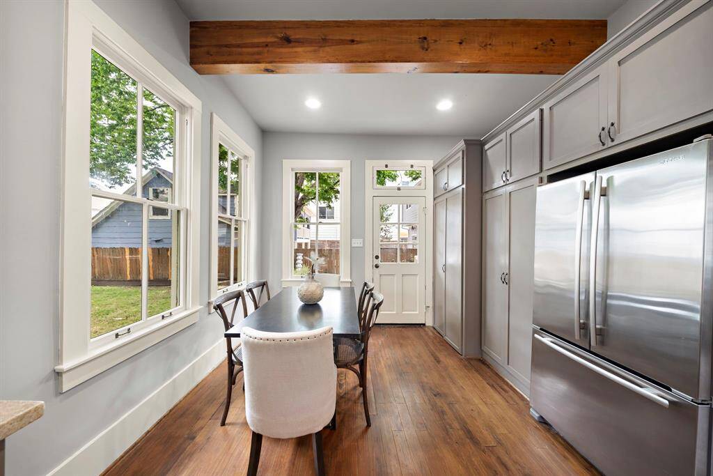 Dining area has 3 large windows letting in so much natural light!! Also note back door and transom window above it, for even more light! Exposed solid wood beam - another feature in this charming historic home!