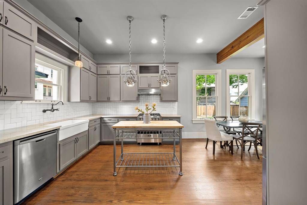 CUSTOM built cabinets in the kitchen. Farmhouse single bowl sink. Restoration Hardware lights above the kitchen island. Note the solid wood floors continue in here