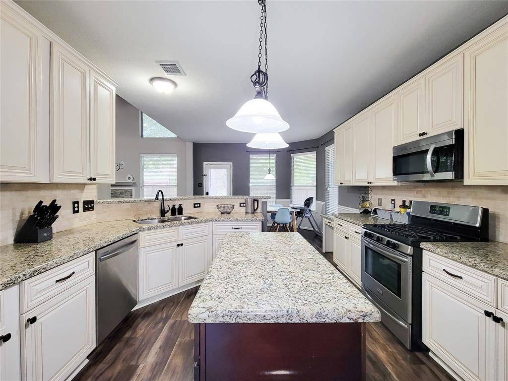 Updated Kitchen with island, cabinets, granite counters, stainless steel appliances & travertine backsplash/
