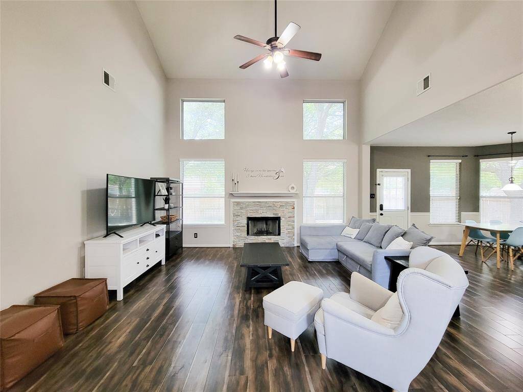 Spacious Living room with high ceilings, stack-stone fireplace & laminate floor. Note the rows of windows to bring the natural light in.