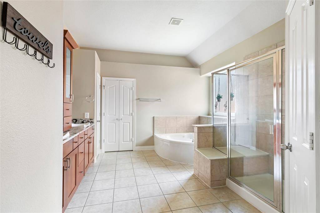 Primary bathroom with dual sinks, jetted tub, separate shower, and large walk-in closet.