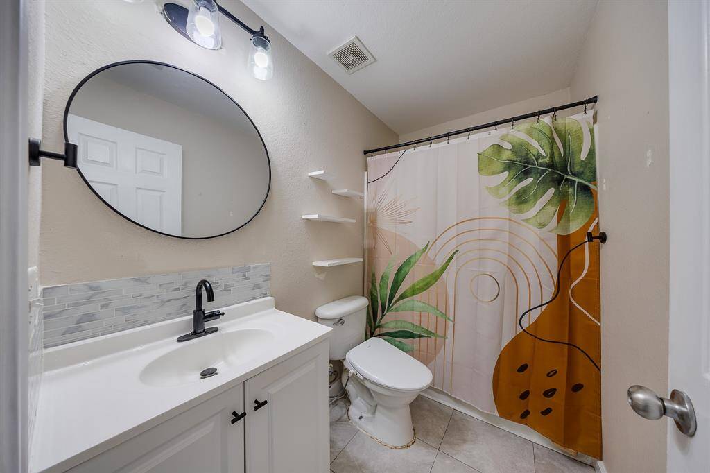 The bathroom downstairs features a beautiful round mirror, adding a stylish and elegant touch to the space.