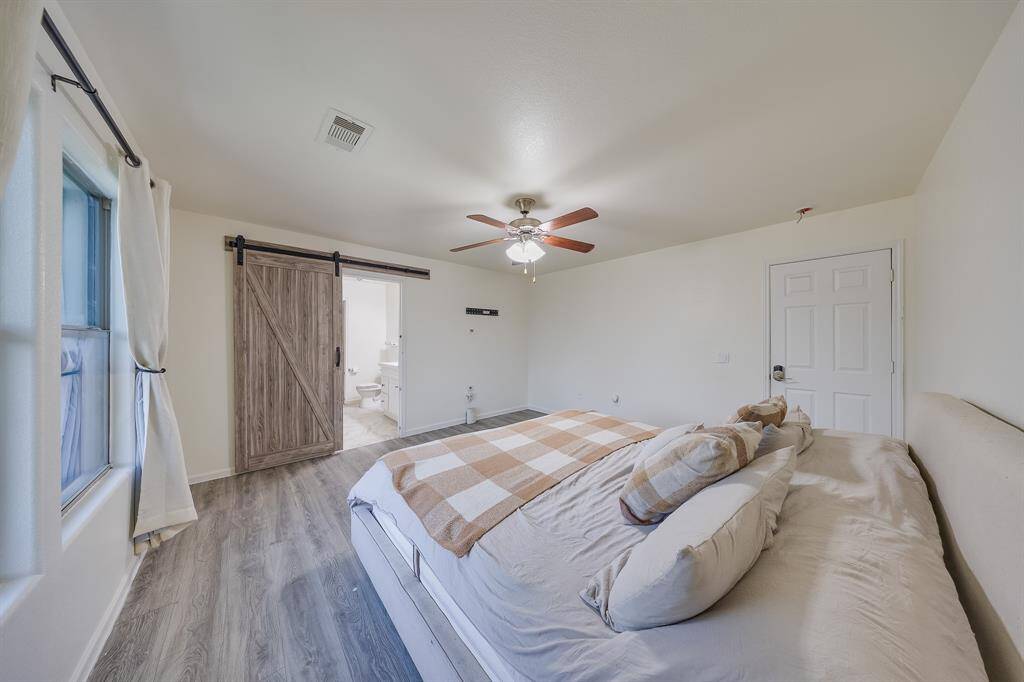 Primary bedroom with wood-like flooring, combining warmth and durability for a cozy atmosphere.