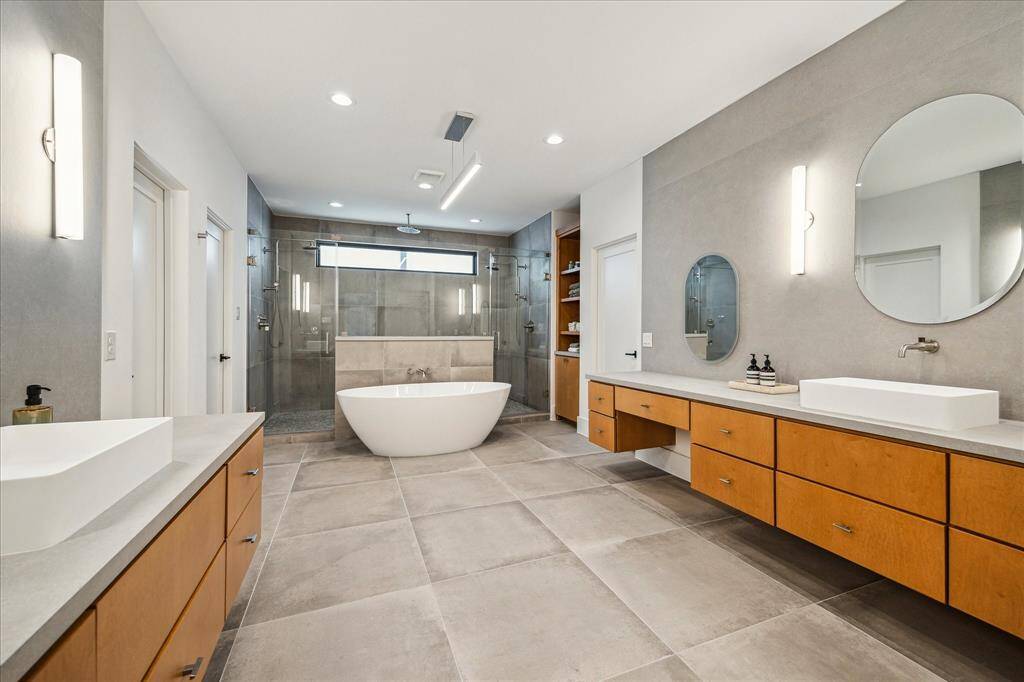 Primary bath features double expansive vanities, expansive walk-in shower and free standing tub.