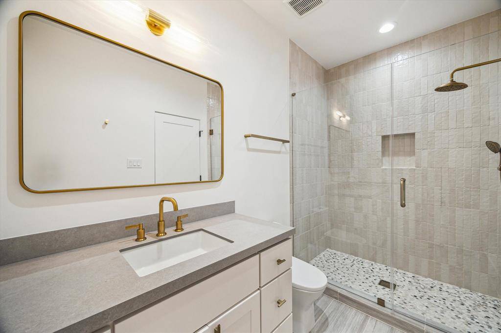 Third bathroom featuring a frameless glass-enclosed walk-in shower, with access from both the bedroom and game room.