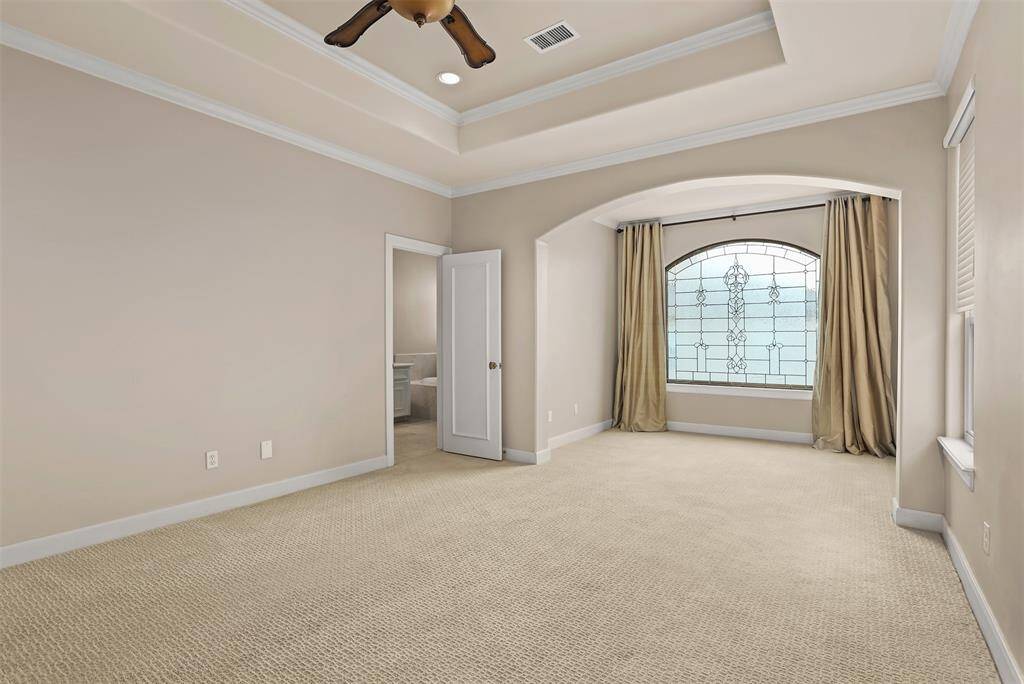 Serene primary bedroom features a cozy sitting area with an elegant custom cut-glass window.