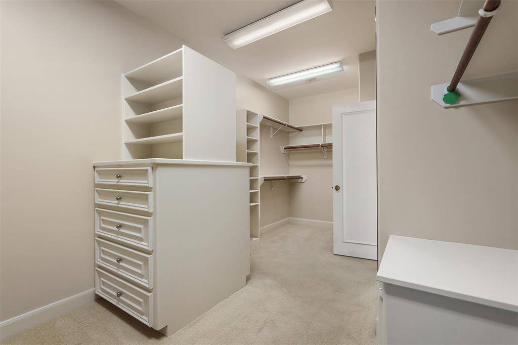 Spacious primary closet featuring custom built-ins for optimal organization.