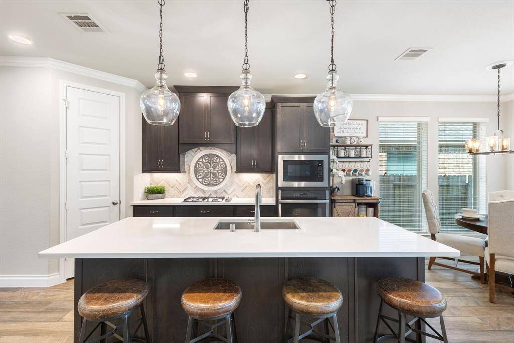 The oversized island serves as the centerpiece of the kitchen, featuring a built-in sink and seating for four, perfect for casual dining or entertaining.