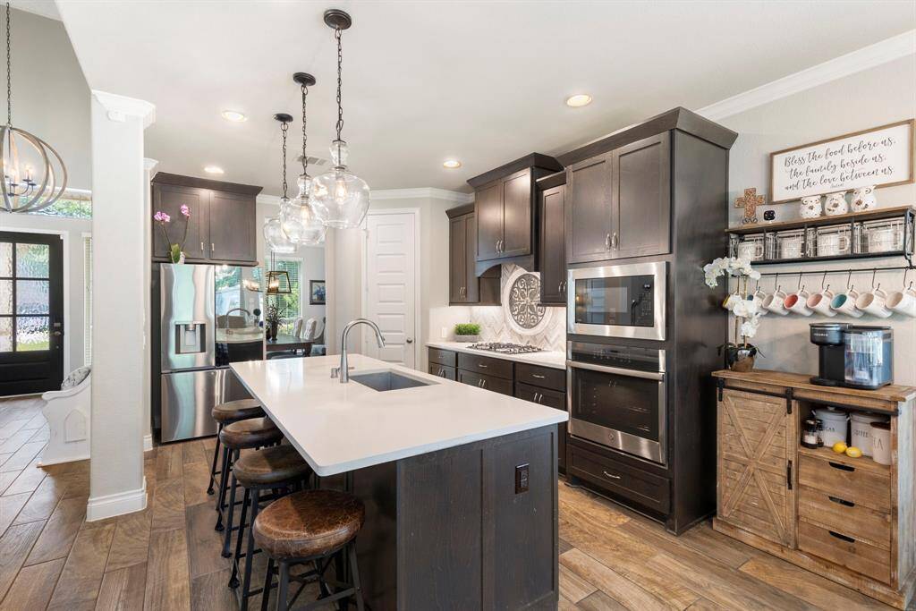 The kitchen showcases stainless steel appliances, wood-look tile flooring, and crown molding, with a dedicated space perfect for a coffee bar or additional storage.