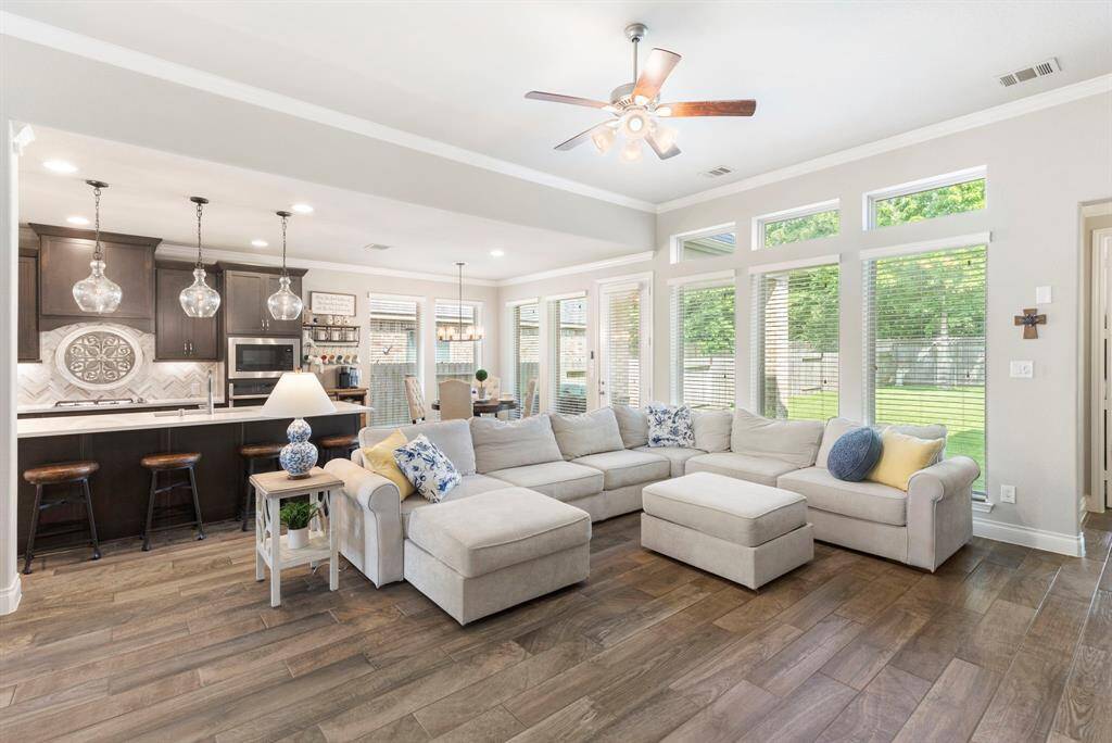 The living room features a spacious open layout and is lined with large windows that bring in natural light and offer a bright and airy atmosphere.