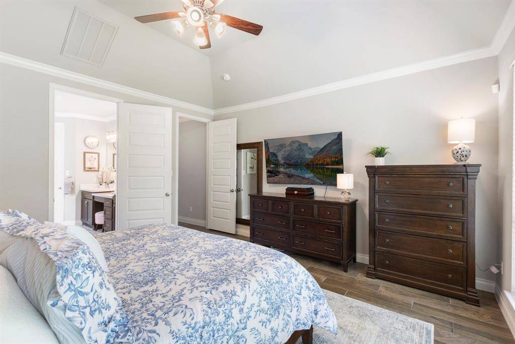 The primary suite features elegant tray ceilings, detailed crown molding, and is generously sized to comfortably accommodate a king-size furniture set with room to spare.