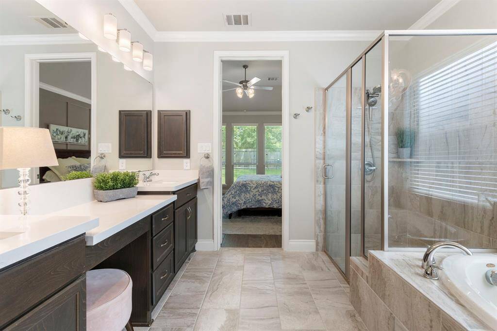The primary bathroom offers tons of counter space, a vanity area, a large shower, and a soaking tub.