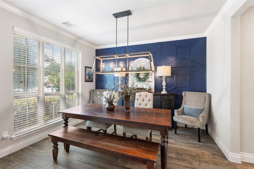 The formal dining room features large windows that fill the space with natural light, crown molding, and a stylish accent wall that adds character and charm.