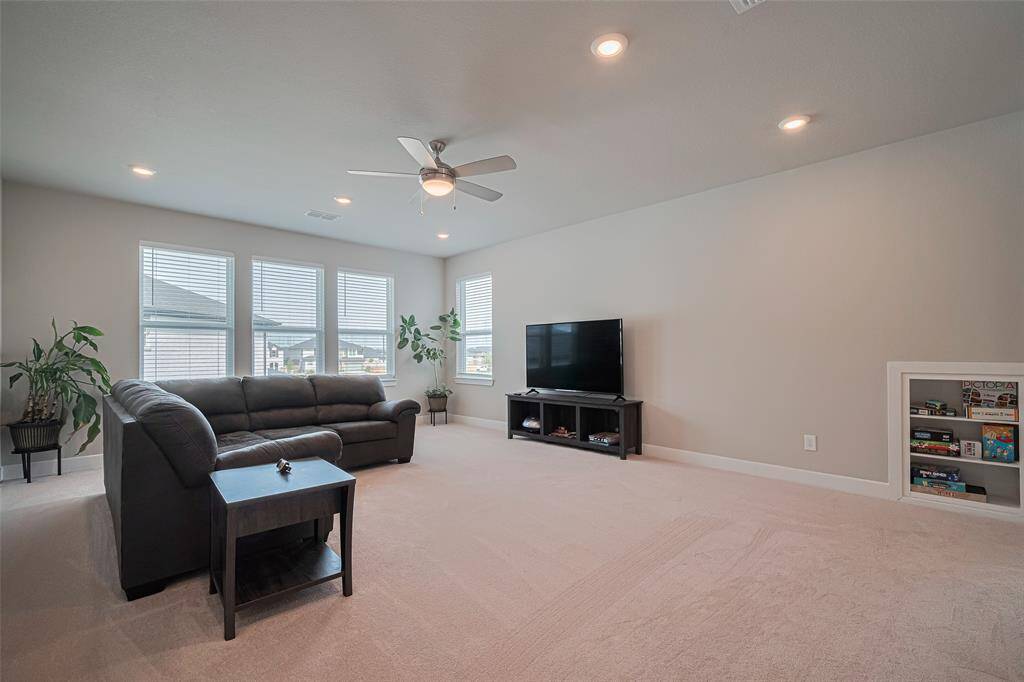 Spacious game room with neutral colors, w/built-in shelving, room for a pool table & ample natural light from multiple windows.