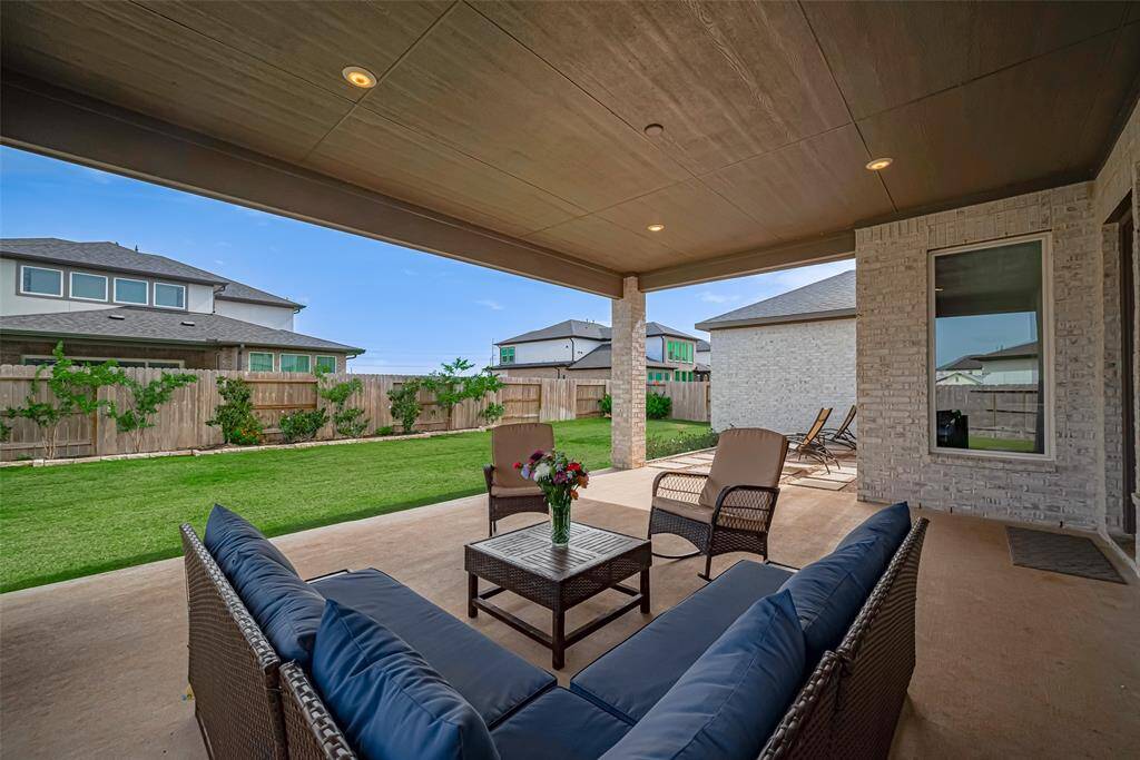 A spacious covered patio with space to relax and a view of a well-maintained backyard, perfect for outdoor relaxation and entertaining.