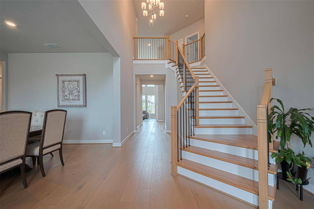 Natural light flows in from large windows, enhancing the spacious feel. The adjacent dining area has elegant seating, and a chandelier provides a warm ambiance.