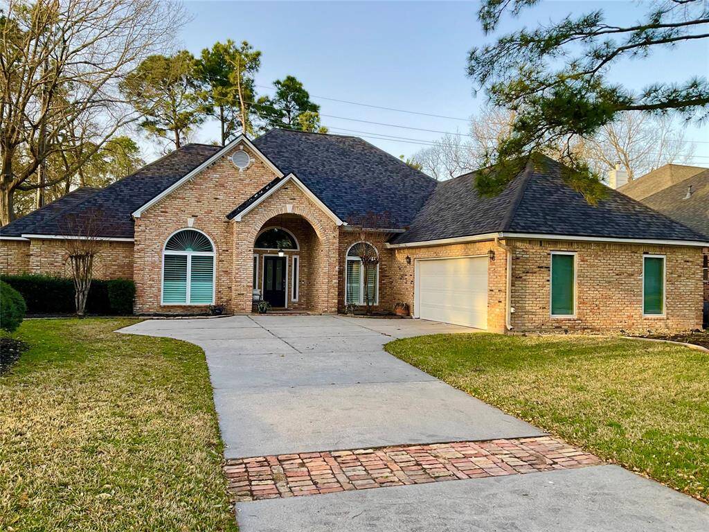 A charming custom brick home with a spacious driveway and a two-car, side load garage. The house features a welcoming arched entryway, large windows, and a well-maintained lawn with mature trees, creating a serene suburban atmosphere.