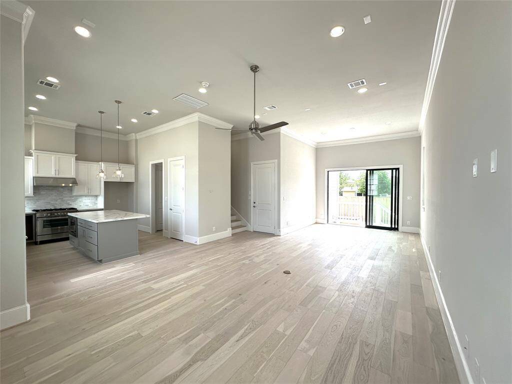 Open Living Room with12 FT Ceilings - Wide Plank wood Floors - Tri-Paneled Glass Doors Open a Future Fenced-in Backyard and Patio