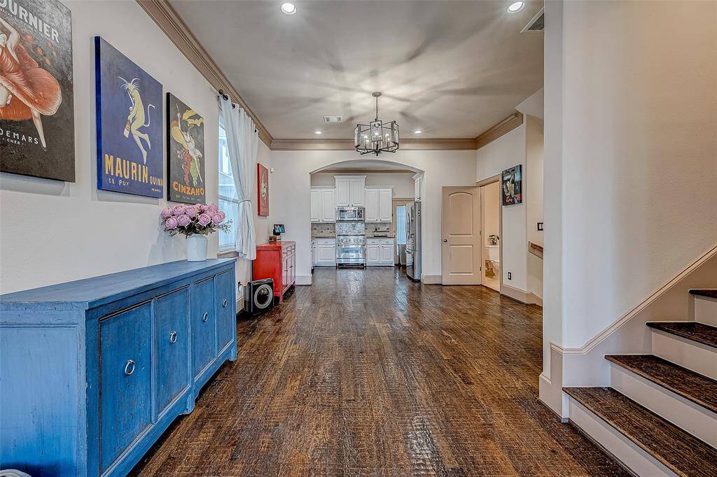 A bright, inviting hallway with hardwood floors leads to a modern kitchen, while a staircase to the right enhances the home's open and spacious feel.