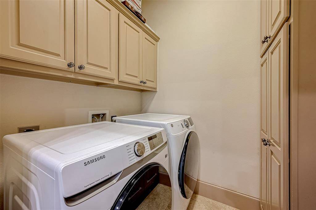 This laundry room features a Samsung washer and dryer set, surrounded by ample  cabinetry for storage