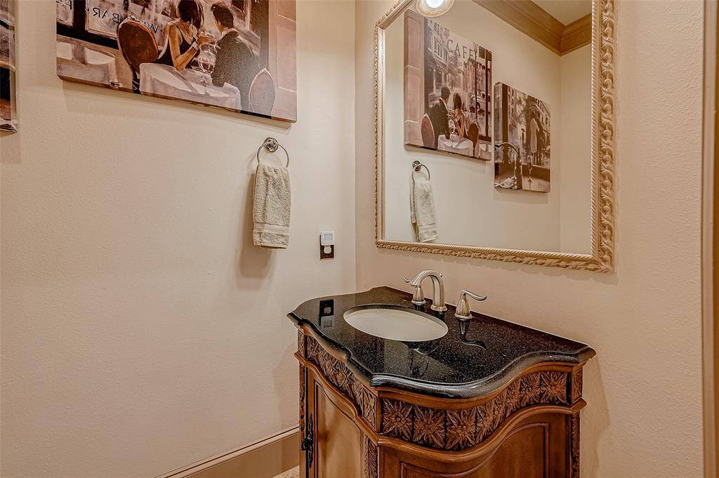 A stylish second-floor half bath features an wooden vanity with a black granite countertop and an elegant oval sink, adding sophistication to the space.