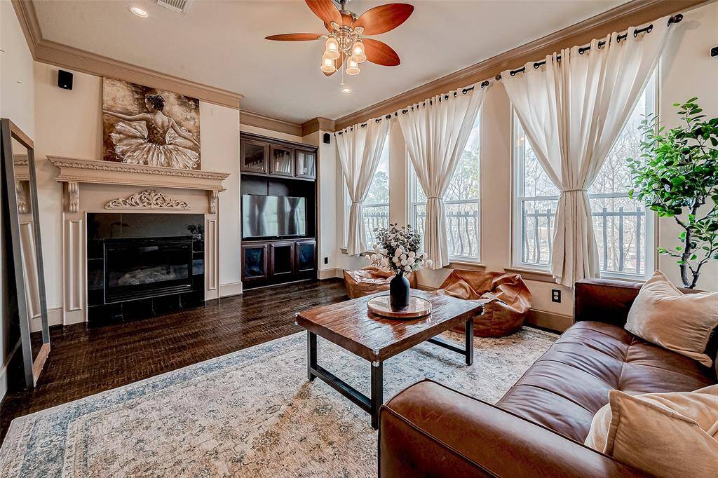 This inviting living room boasts a cozy fireplace, elegant built-in shelving, and a wall of large soundproof windows that fill the space with natural light.