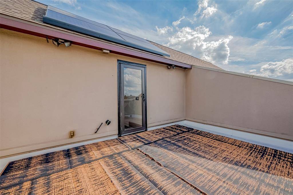 The rooftop terrace features a glass door and solar panels on the roof, providing a private outdoor space with downtown views