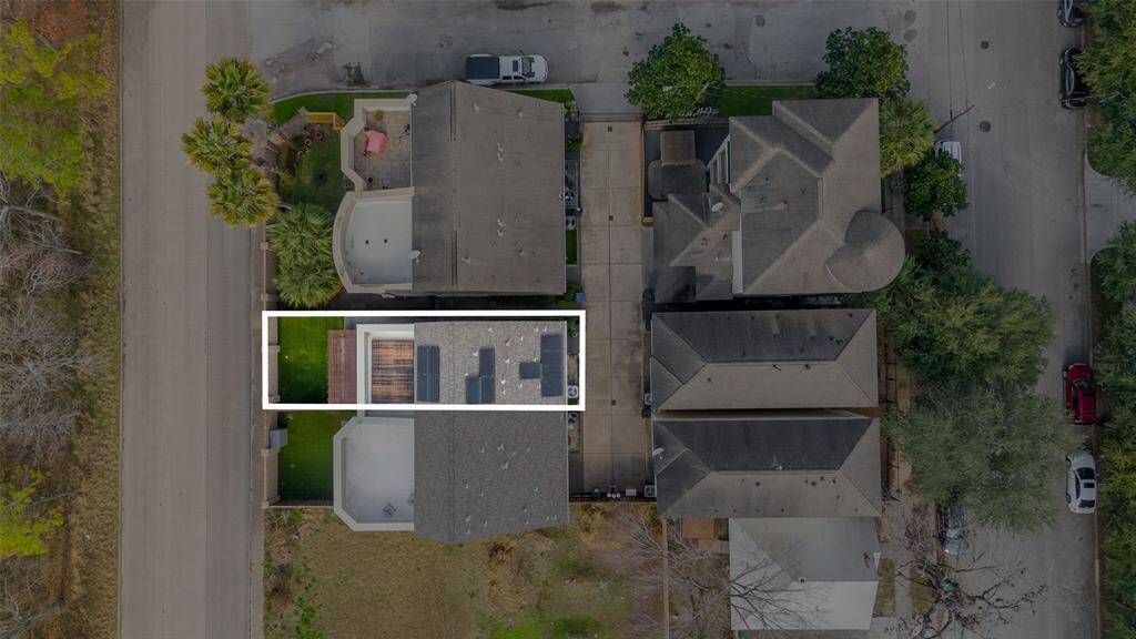 Aerial view of a well-maintained property with a manicured lawn, rooftop patio, and easy street access.