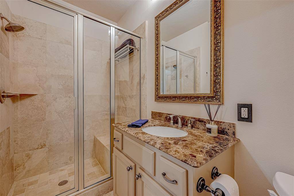 The first-floor bathroom offers a glass-enclosed shower, tiled walls, sleek vanity with undermount sink, and a stylish countertop