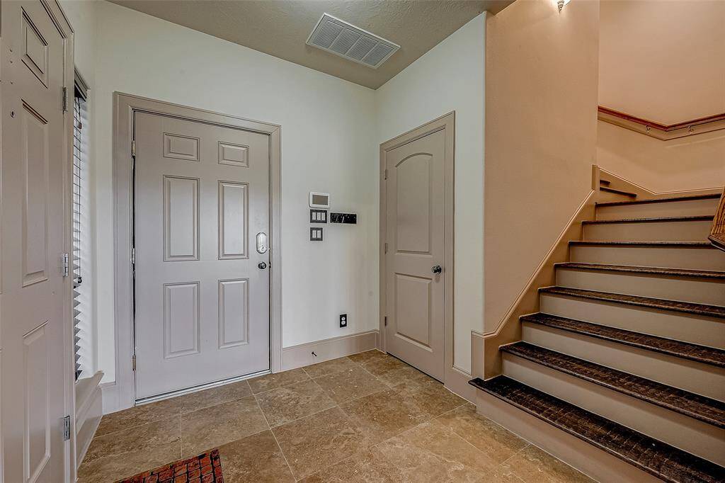 This entryway features a neutral-toned front door and tile flooring, leading to the second floor