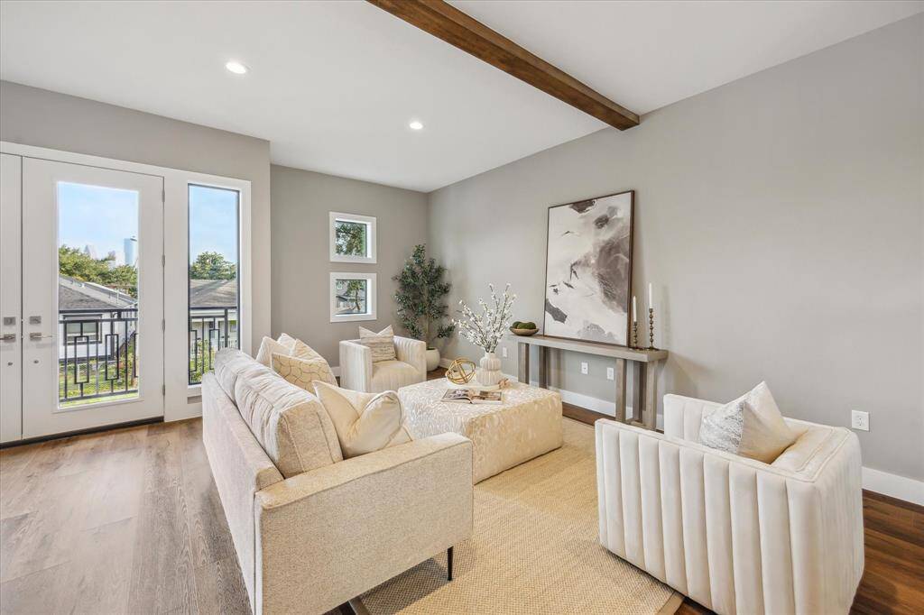 Soft natural light, neutral tones, and clean modern lines create a calm and welcoming vibe in this beautifully styled living area—complete with wood beam accents and Downtown peeks just outside the French doors.