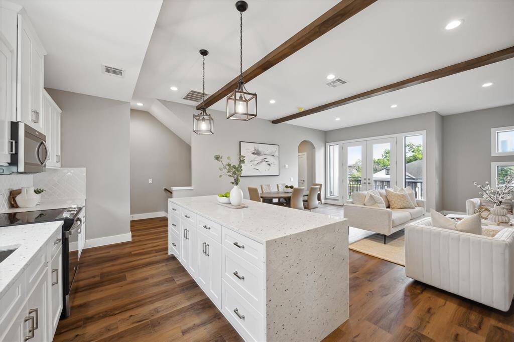 The sleek waterfall-edge island adds a luxurious statement to the heart of the home—anchoring this bright, open kitchen with modern elegance and functional flow.