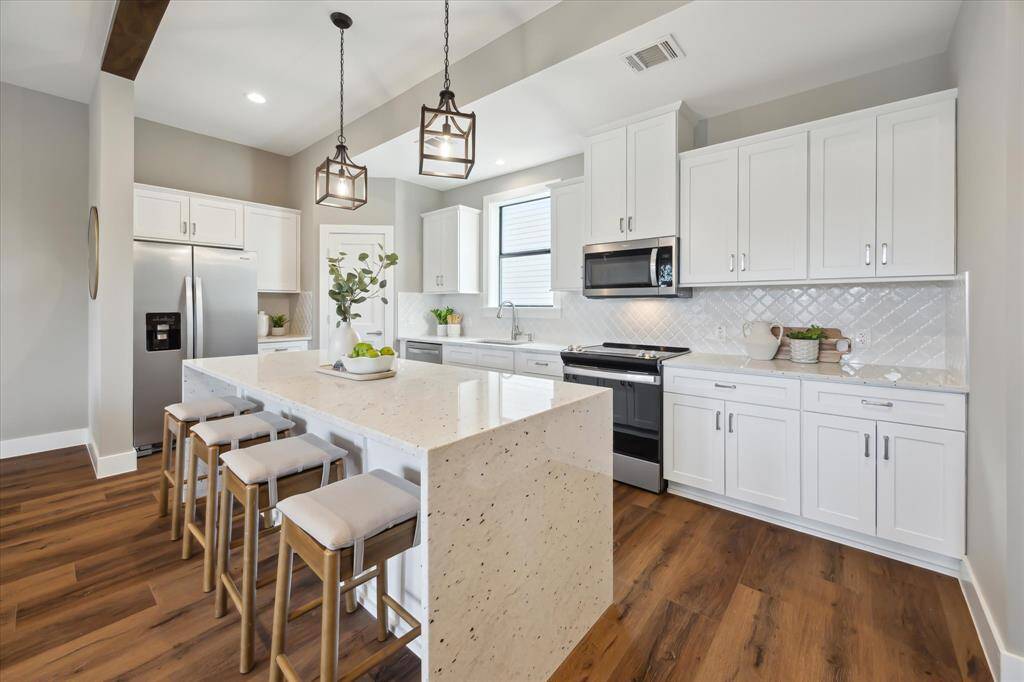 The classic white tile backsplash, laid on a diagonal for added visual interest, pairs beautifully with expansive quartz countertops—offering ample prep space for culinary enthusiasts and casual cooks alike.