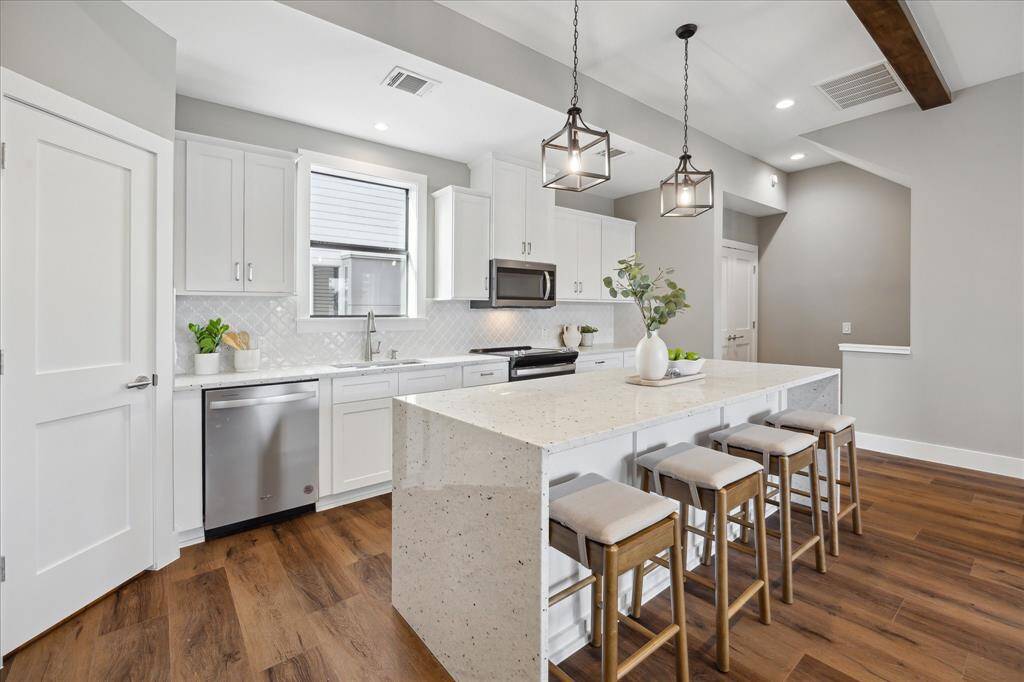 Designed to impress, this sunlit kitchen features clean lines, ample bar seating, and a crisp modern palette—blending beauty and function in a space that’s ready for your personal touch.