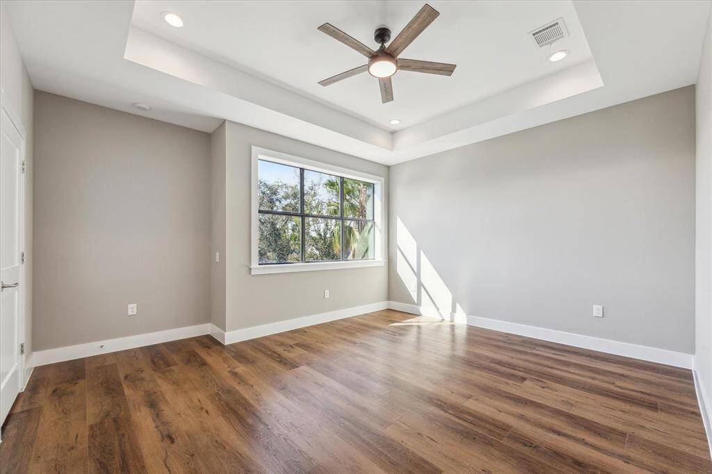 Spacious and serene, the third-floor primary bedroom features a recessed tray ceiling, luxury vinyl flooring, and a large picture window for a bright and airy retreat.