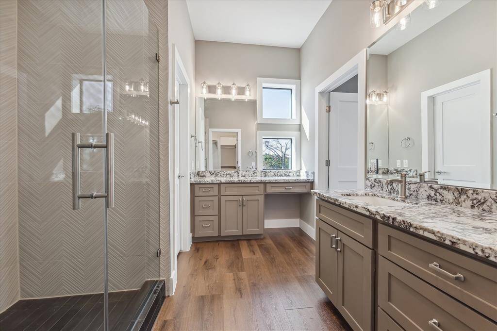 This bright and airy retreat features dual granite vanities, custom cabinetry, and a dedicated makeup area—positioned to enjoy soft natural light from adjacent windows just across the hall.