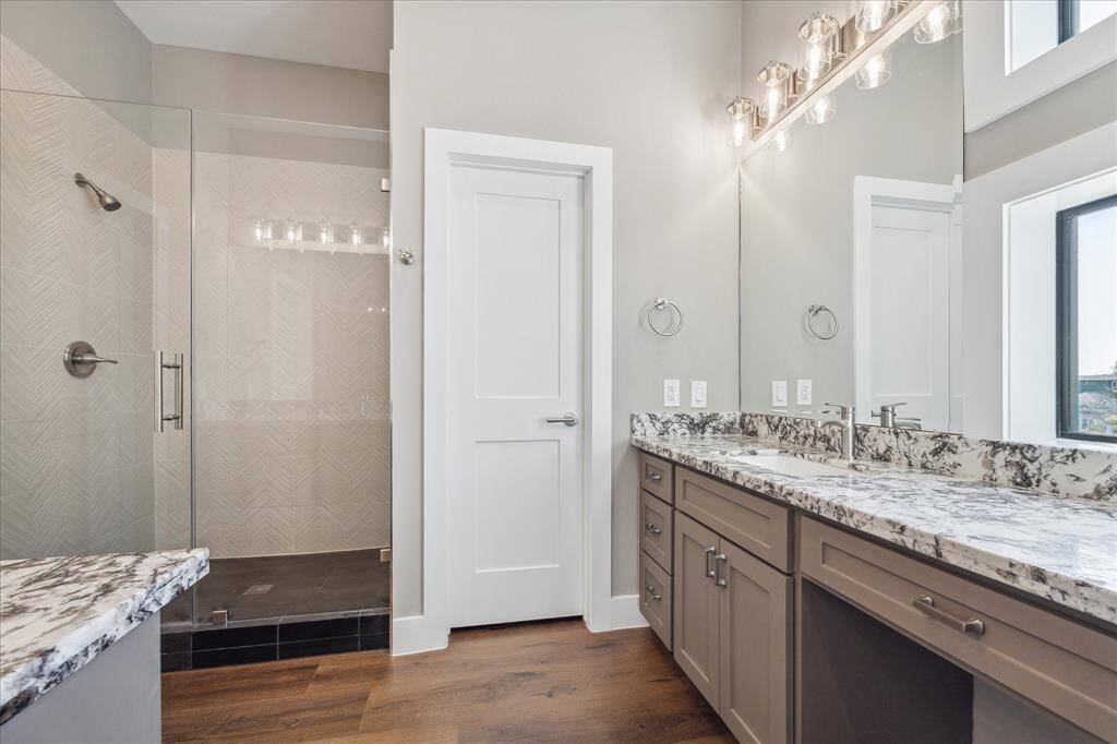 The walk-in shower features floor-to-ceiling tile in an elegant herringbone pattern and sleek glass enclosure—designed for both style and comfort.